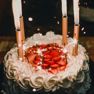 Celebrate with a festive strawberry-topped birthday cake adorned with sparkler candles, creating a joyful atmosphere.